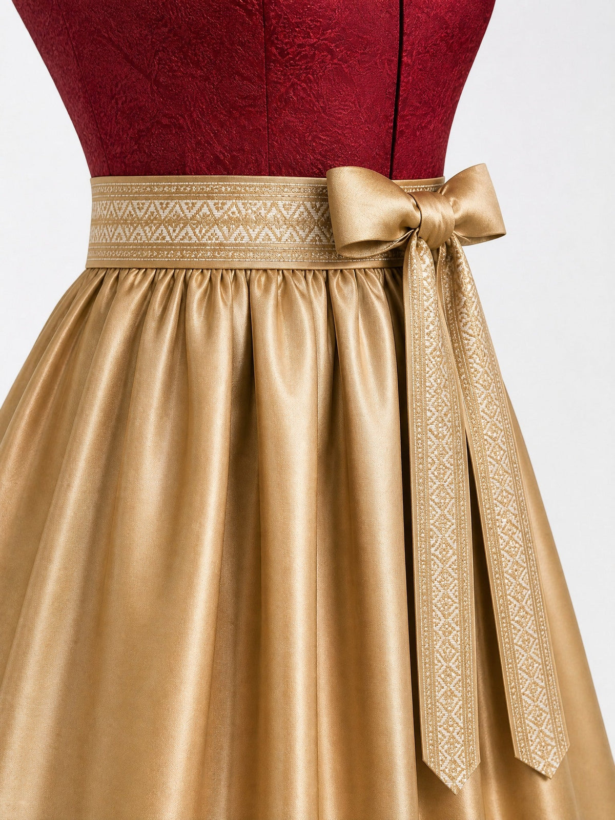 Dirndl Lia in Cranberryrot mit Antikgold Schürze - Detailansicht Taille und Schleife
