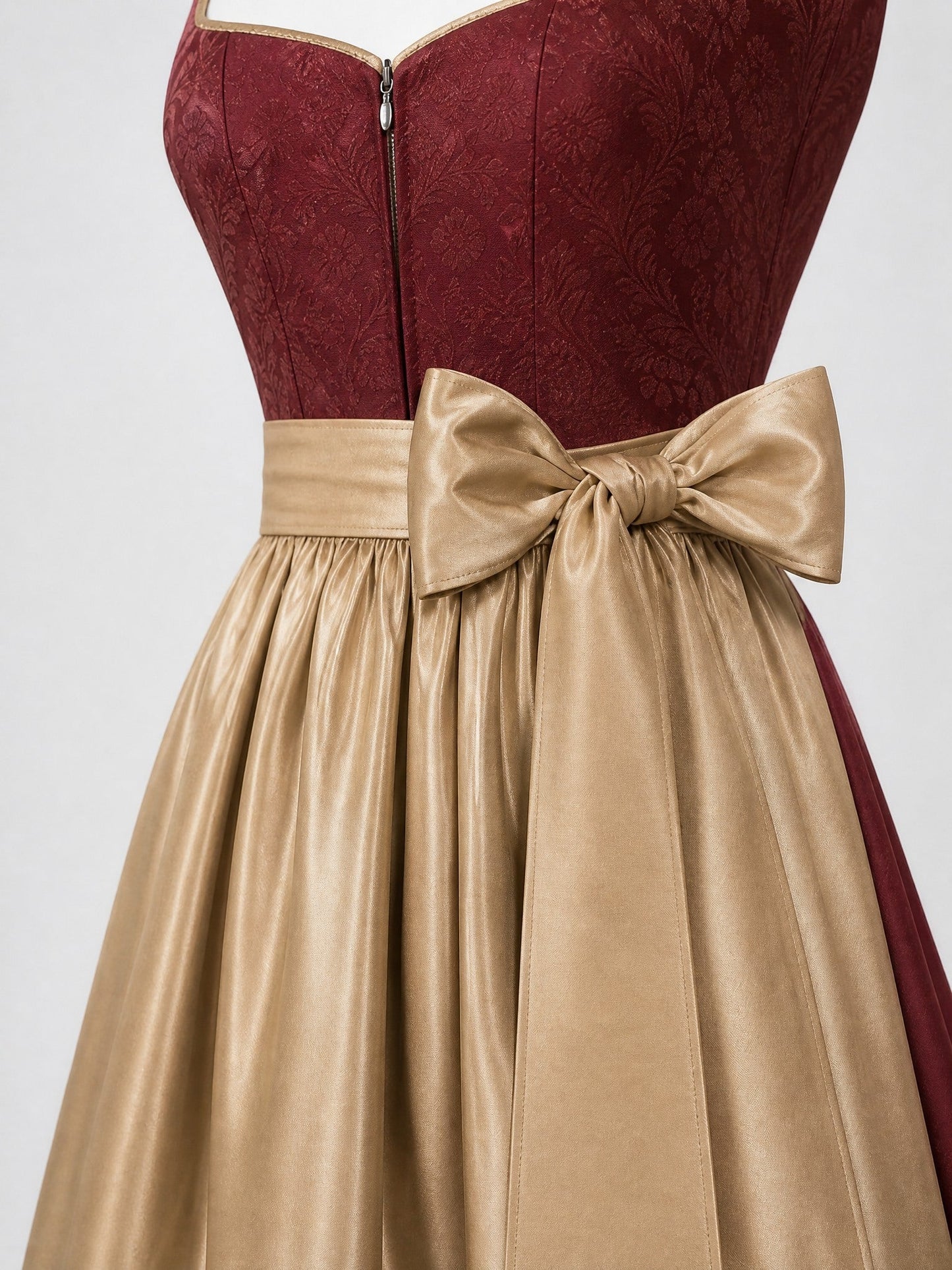 Dirndl Lara in Cranberryrot mit Antikgold Schürze - Detailansicht Taille und Schleife
